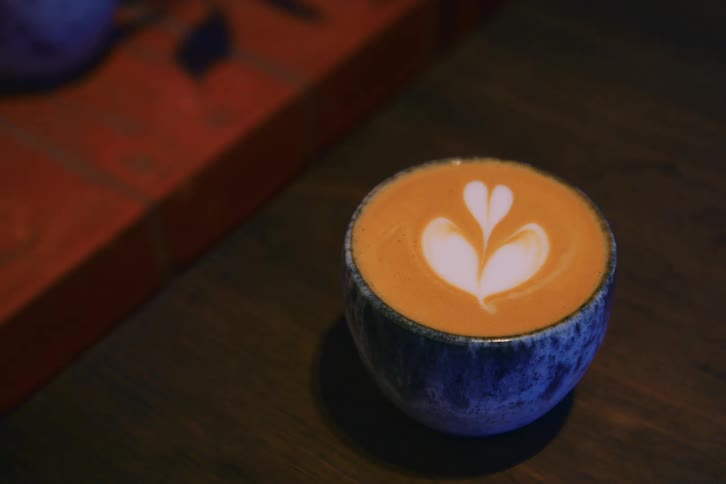 Pale cream forms a shape in the foam of a coffee beverage