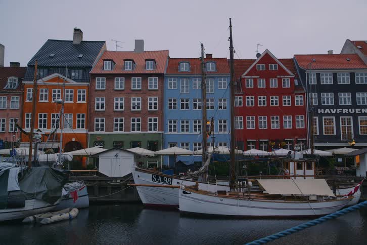 Colorful buildings line a canal with docked boats in an urban area