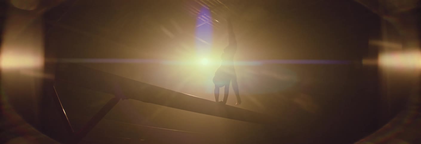 A woman doing a gymnastics training routine on a balance beam