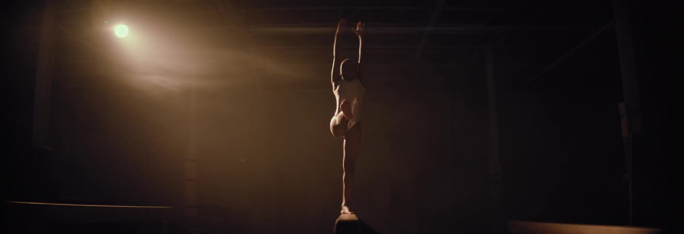 A girl practicing gymnastics on the balance beam loses her footing