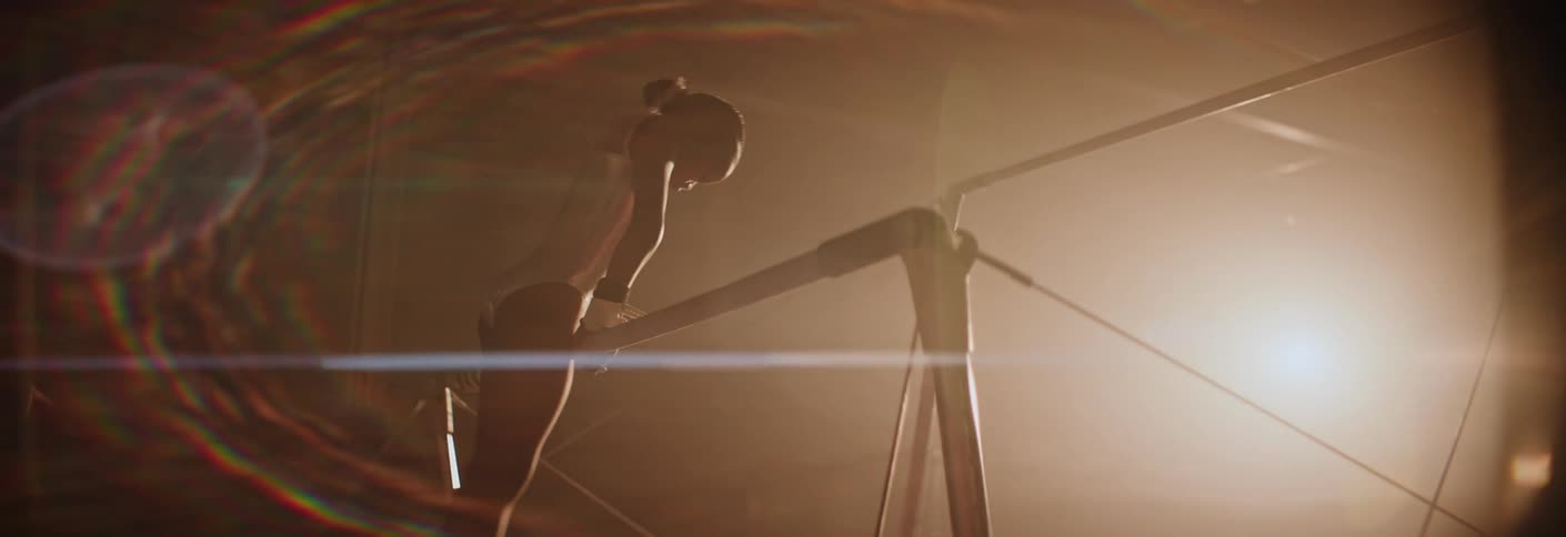 A young girl lifts herself onto uneven bars in a gymnastics competition
