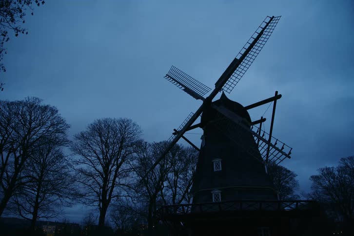 A large old fashioned windmill is by the trees