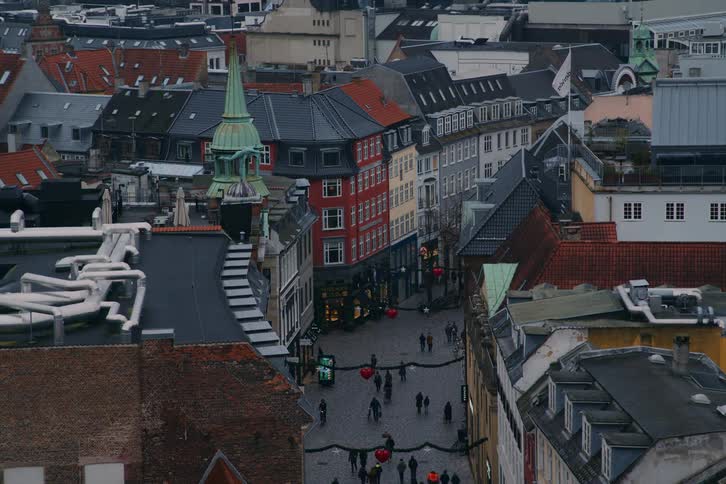 Aerial view of a historic street with old buildings varied rooftops and pedestrian movement between urban facades