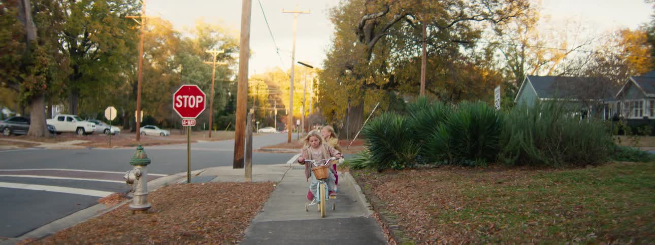 The little girl rides her bicycle on the sidewalk
