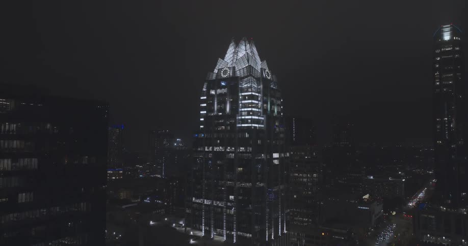 The tall buildings are brightly lit at night