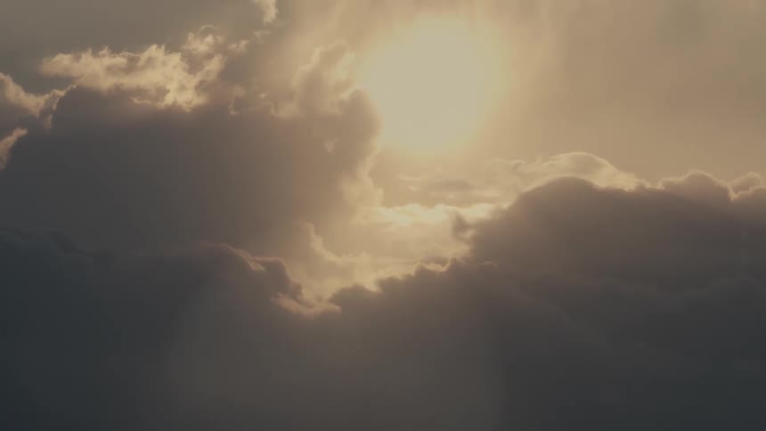 Band of sunlight reflects on the ocean beneath a dark sky with dense clouds on the horizon
