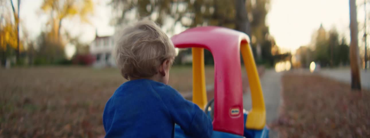 A child pushing a toy car outdoors