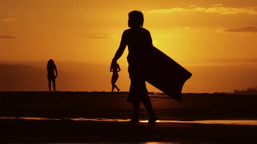 Silhouetted people playing and enjoying a relaxing vacation along the beach at sunset