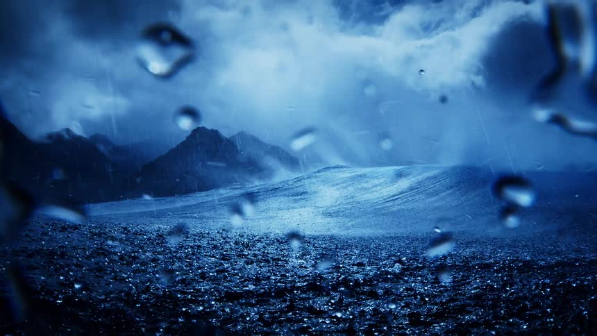Rain falls onto the ocean as a wave swells near the shore during a moonlit night