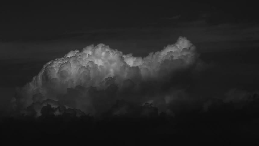 Dense cloud formation highlighted by light and shadow contrast in a dark sky
