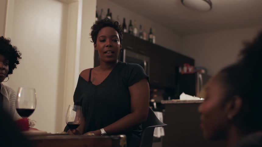 Group of women gathered around having some drinks and talking indoors