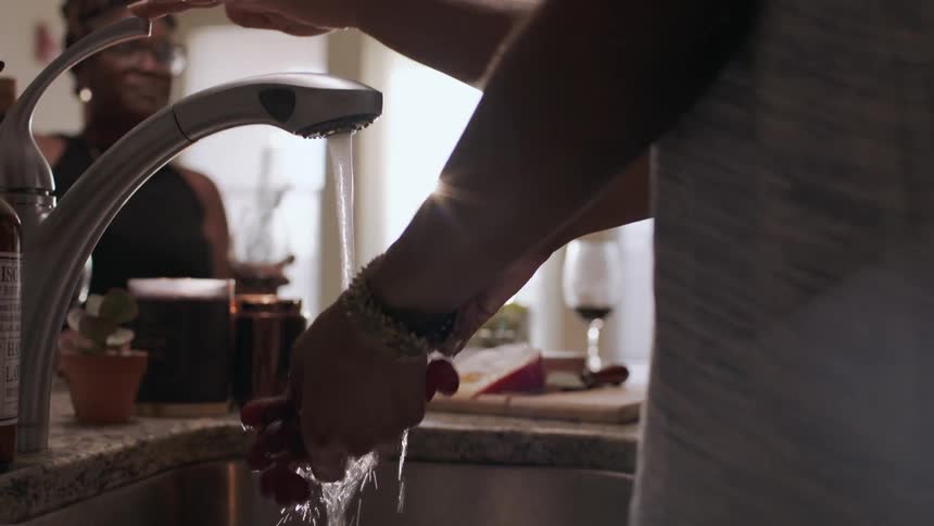 A woman washes grapes in the sink