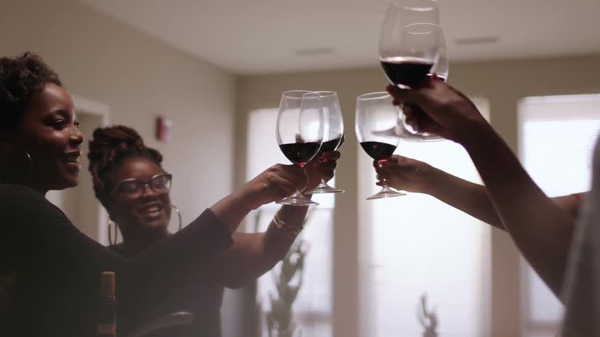 Women toast glasses in a dining room