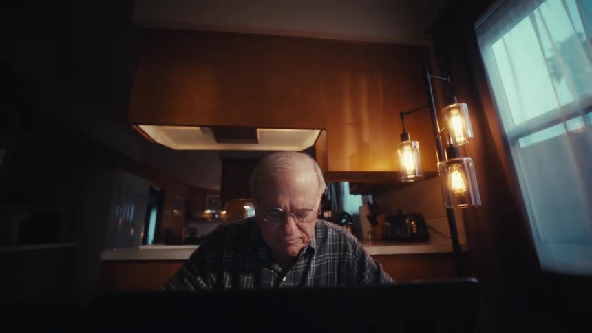 Man sitting at desk a typing on a laptop computer