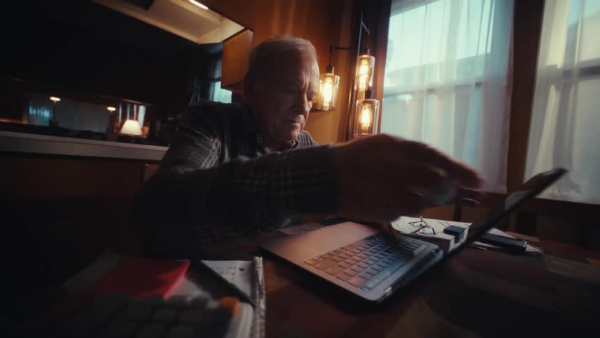 A man sitting down and opening up a laptop