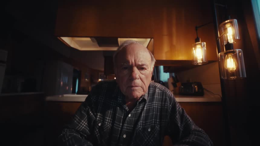 Man sits at the kitchen table typing on a laptop in the evening