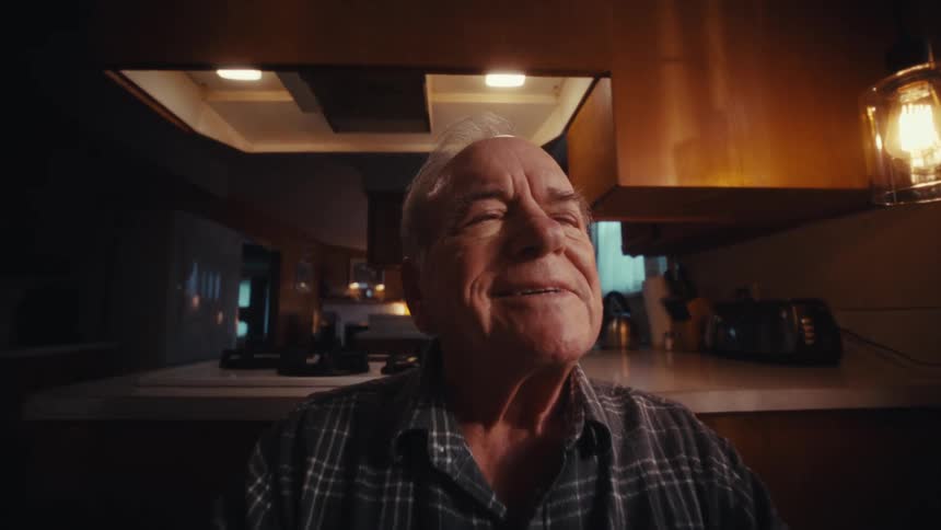 Elderly man sits thoughtfully at an office desk