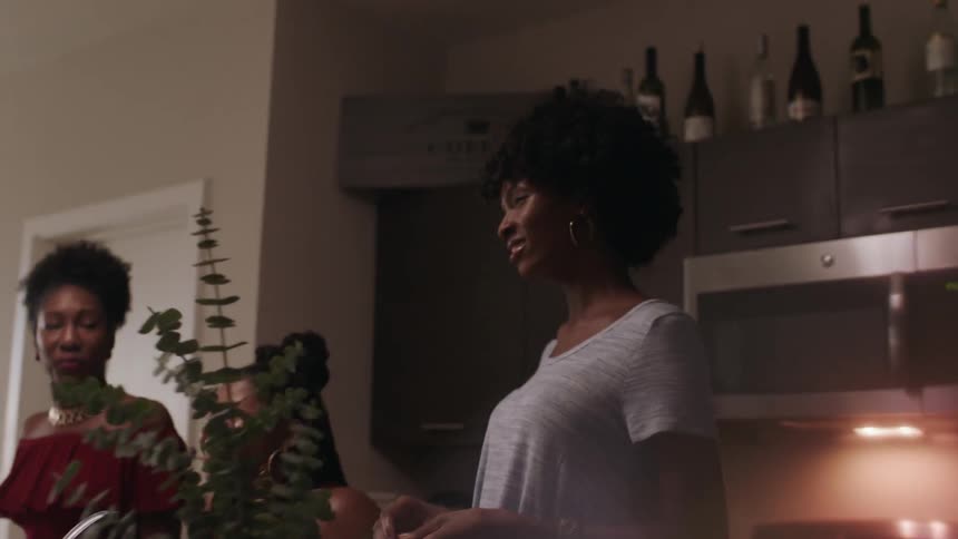 A group of women talk together in the kitchen
