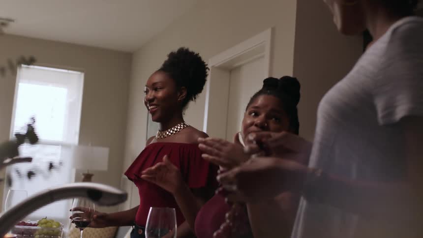 Several women standing around having some drinks and talking indoors