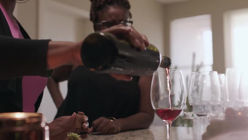 A woman pours wine for a friend