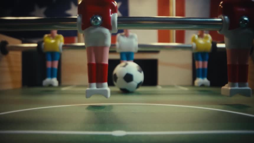 Soccer ball near the goal on a foosball table with aligned player figures
