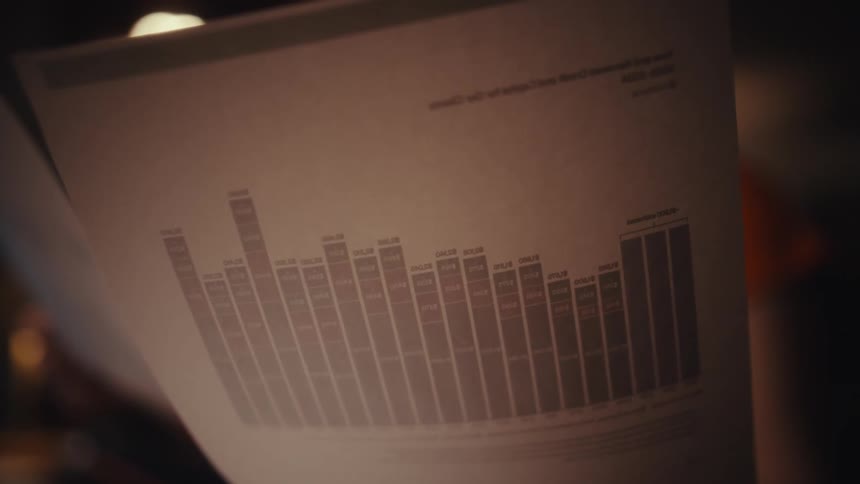 A woman reviewing documents beside her laptop while working late in a dimly lit home office