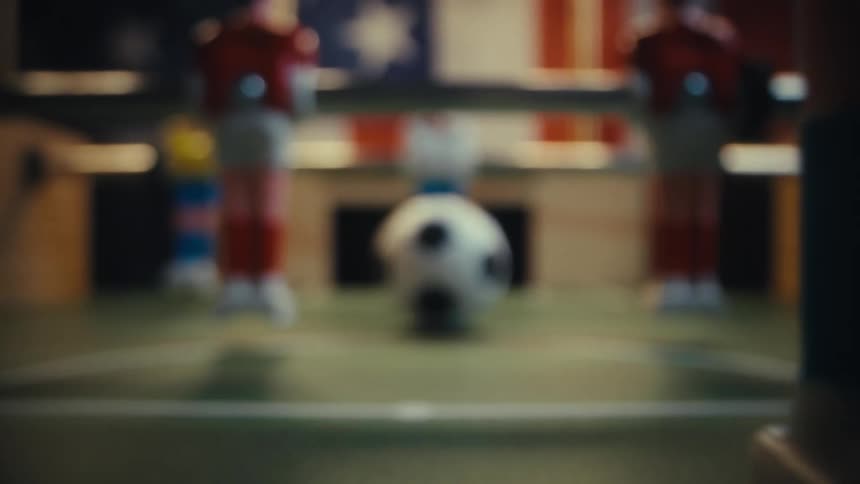 Closeup of a red and yellow foosball players and the ball on a tabletop game