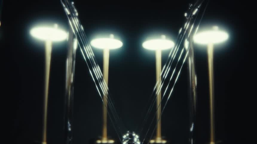 A metal pendulum swings between glowing lights in a dark futuristic space