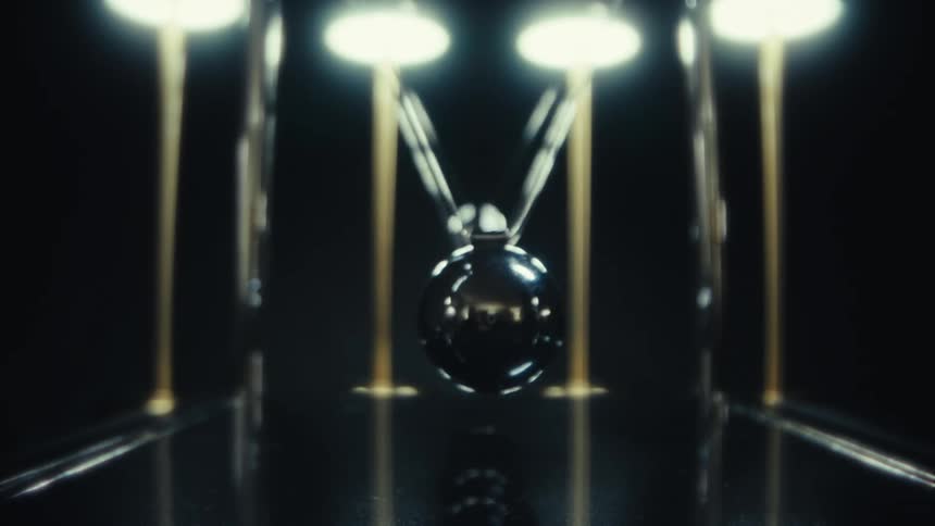 Metal sphere swinging between aligned rods in a pendulum device