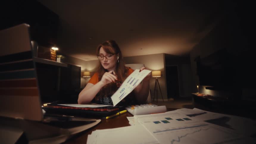 A woman showing papers to a laptop camera