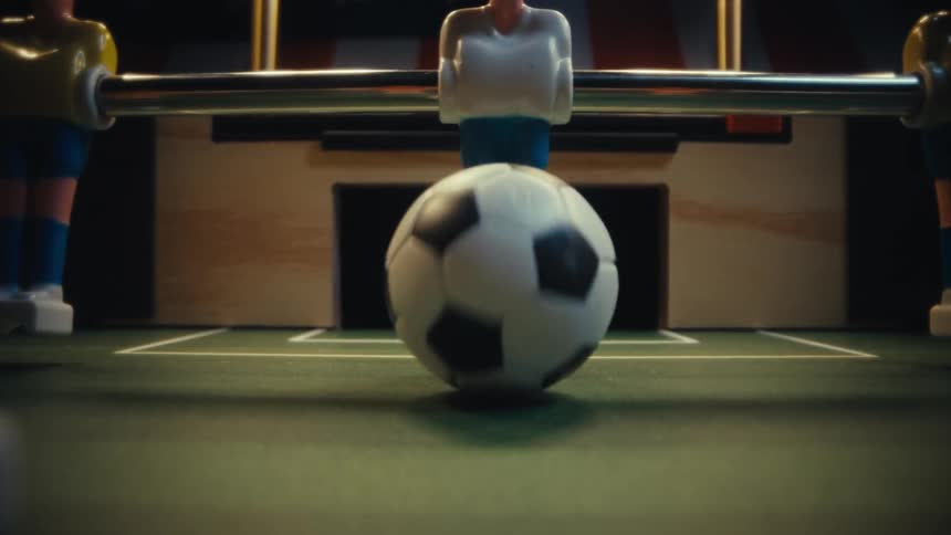 Ball running along a foosball table is blocked by a figure
