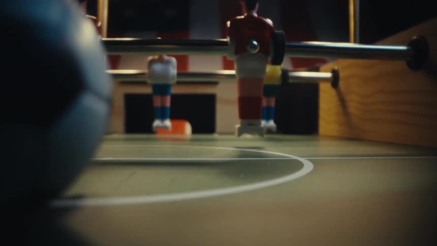 Plastic men on bars and a ball on the foosball table