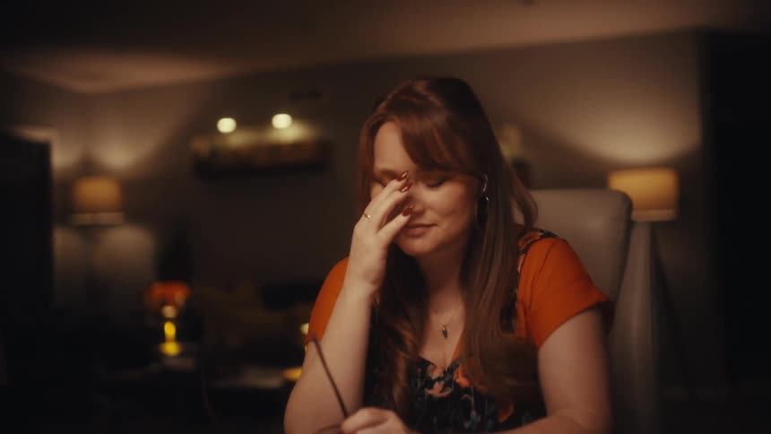A stressed woman working late at her laptop in a warmly lit home office