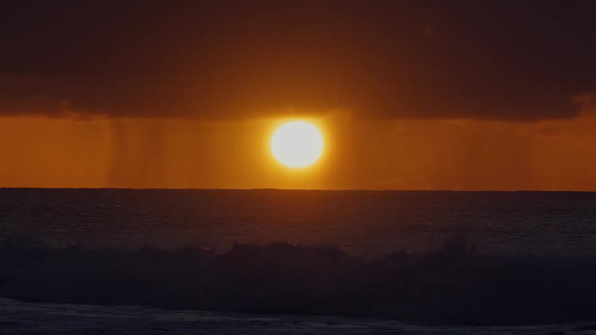 A view of waves on the ocean in front of a sunset