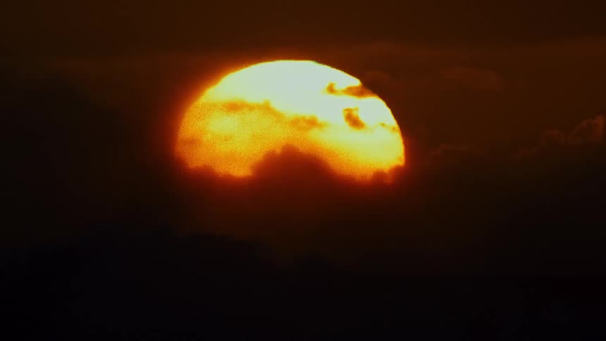 Rough seas with the sun on the horizon and a reddish sky