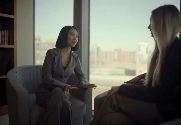 Two women sitting near windows in a room talking