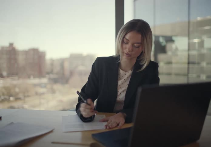 Woman writing on a document while seated at an office desk