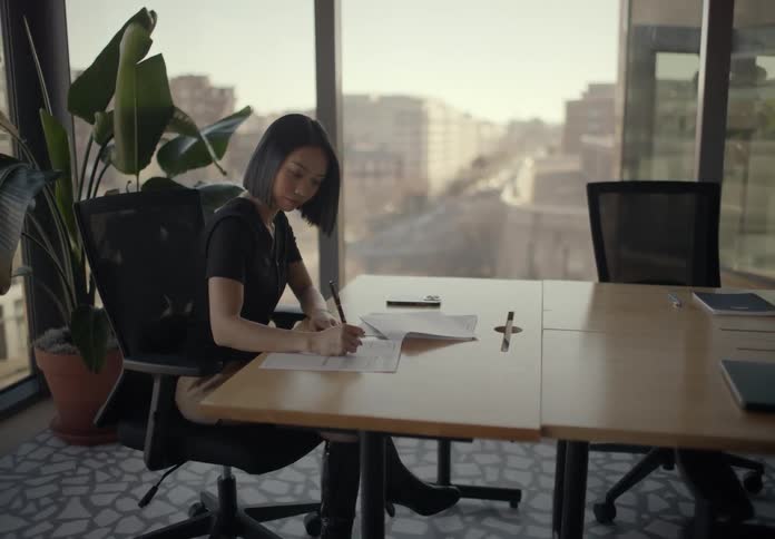Woman sitting at a table in an office filling out paperwork
