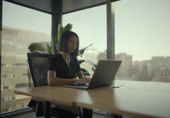 Woman sitting typing on a laptop in an office room