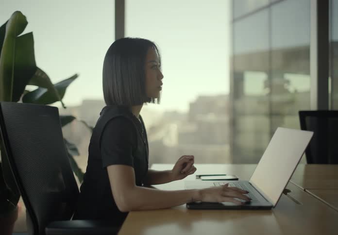 Woman sitting at an office table typing on a laptop computer