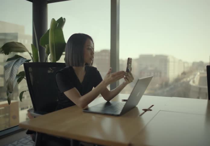 A woman using a smartphone and a laptop