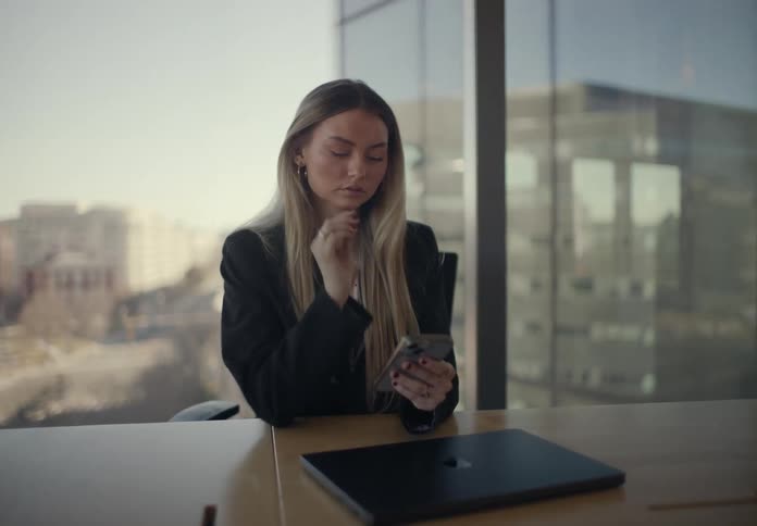 Woman sitting at an office desk and using a smartphone