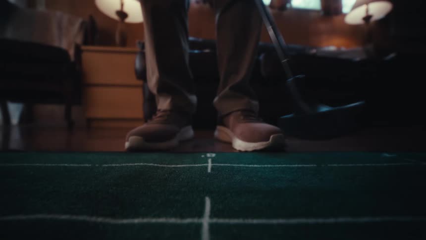 A person hits a golf ball with a putt
