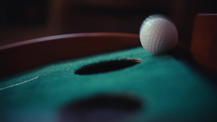 A golf ball going into a cup