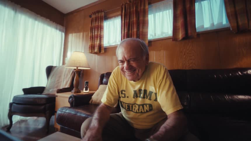 The man smiles while looking at his laptop