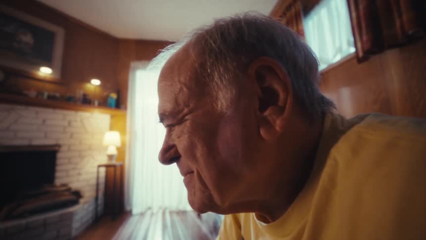 Elderly man sitting in the living room using a laptop
