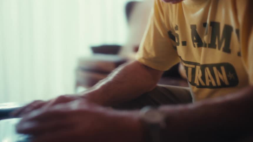 Man sitting on the living room couch typing on a laptop computer on the table
