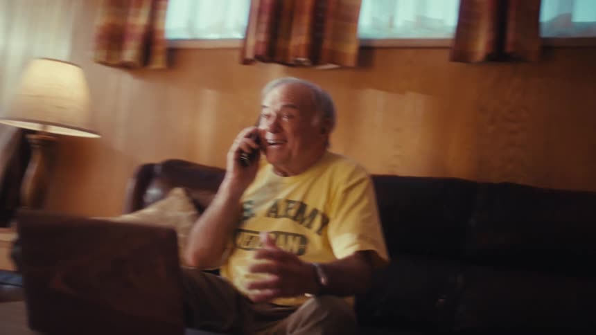 Elderly man sits excitedly chatting on the phone