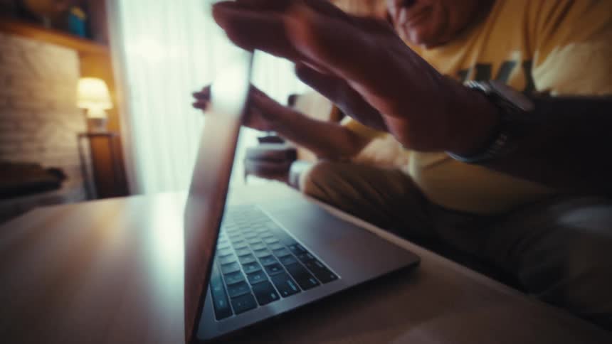 Elderly man closing a laptop