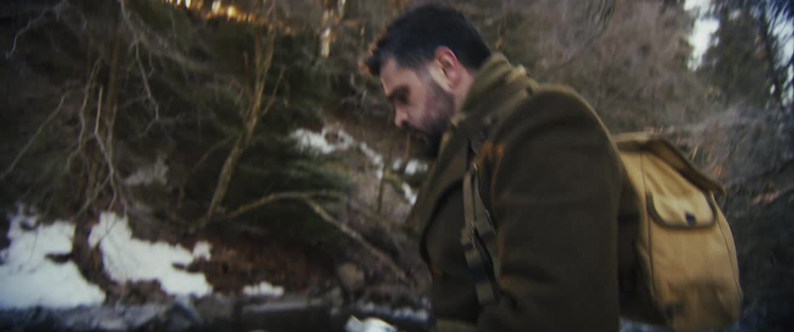 A man filling a water bottle from a stream